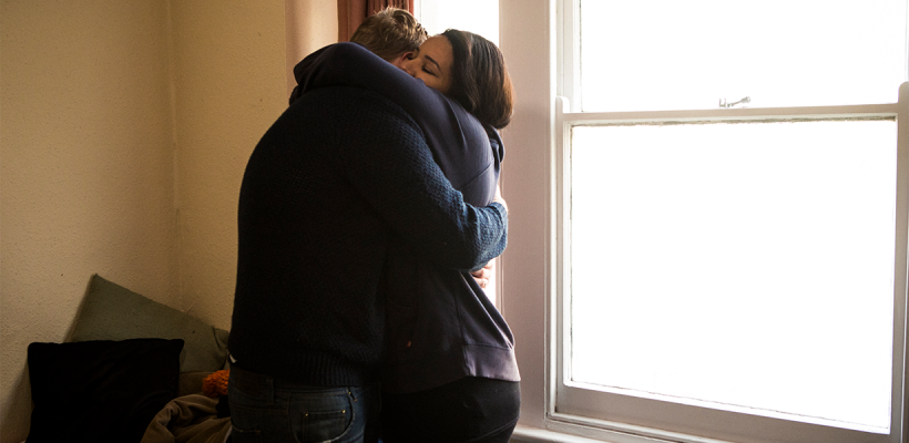 Two young women hugging in their hostel room.